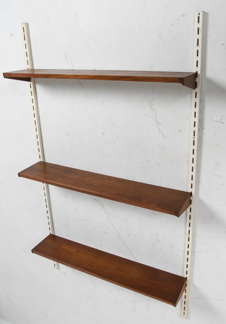 KAI KRISTIANSEN DANISH TEAK WALL SHELVES C. 1960S: For FM Mobler. Steel wall brackets with (3) teak shelves. Adjustable heights. Tagged to back of shelf. Denmark, circa 1960s. Dimensions: Shelves H 3.5" x W 34" x C 7". Wall Brackets 60". Condition: Mi