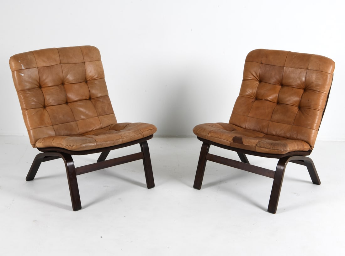 PAIR OF ATTR. INGMAR RELLING LEATHER LOUNGE CHAIRS: Beech frames with brown leather cushions and suede upholstery to frames. Norway, circa 1970s. Dimensions: H 33.5" x W 23.5" x D 24" x SH 17". Condition: Scuffs, rubs, and fading to leather. Few paint