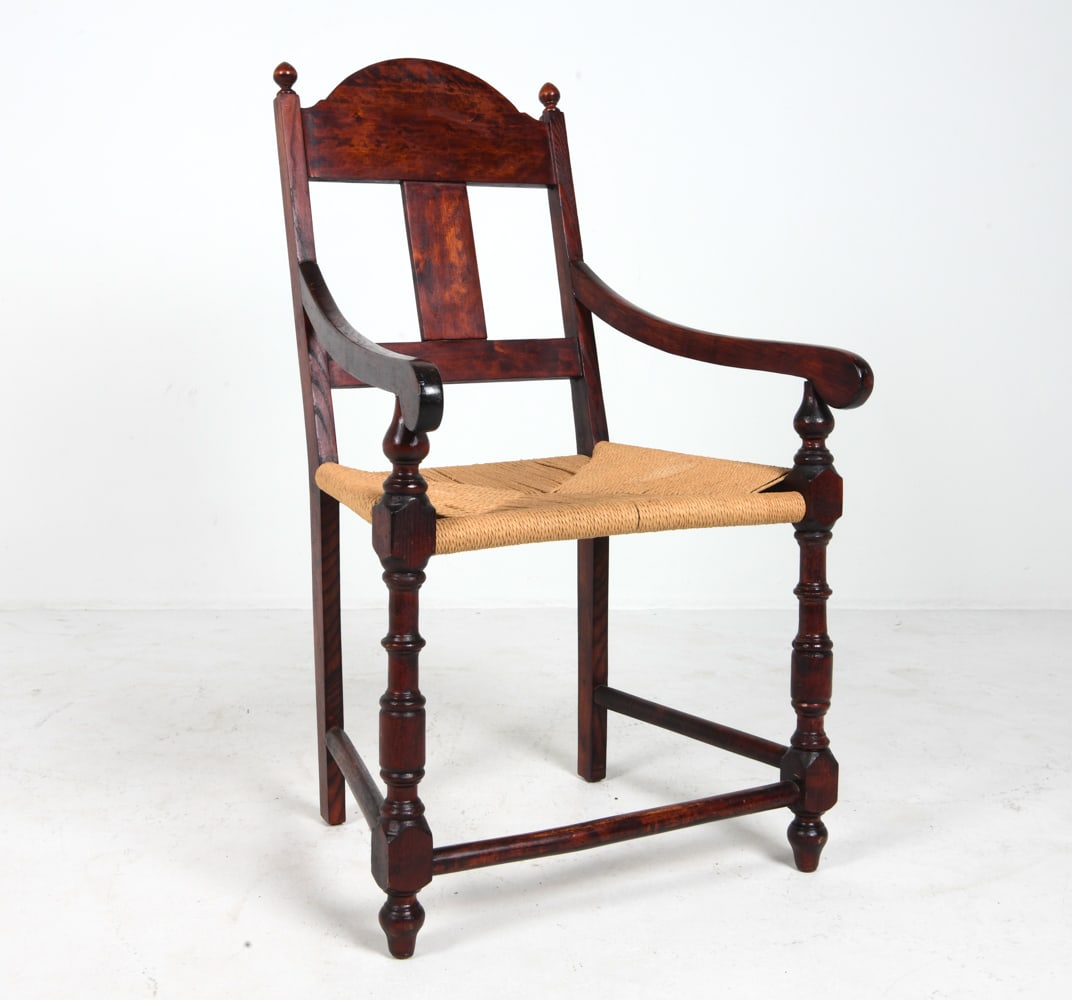 PROVINCIAL STYLE OAK & RUSH ARMCHAIR: Oak armchair in dark stain. Rush seat. Dimensions: H 38.75" x W 23" x D 25.5" x SH 18". Condition: Evidence of old worming, not active. Wear consistent with age and use.