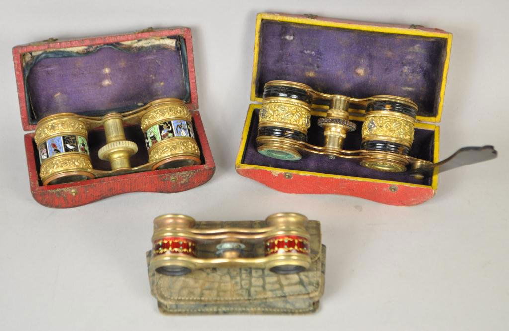 GROUP OF THREE 19TH C. OPERA GLASSES: with their case. Dimensions: brass,red enamel & green stones H 1 1/4"in x W 3.5"in brass,tortoiseshell & mother of peal H 2"in W 4.5"in brass, with enamel design H 1 7/8"in W 4" in Condition: as is ve