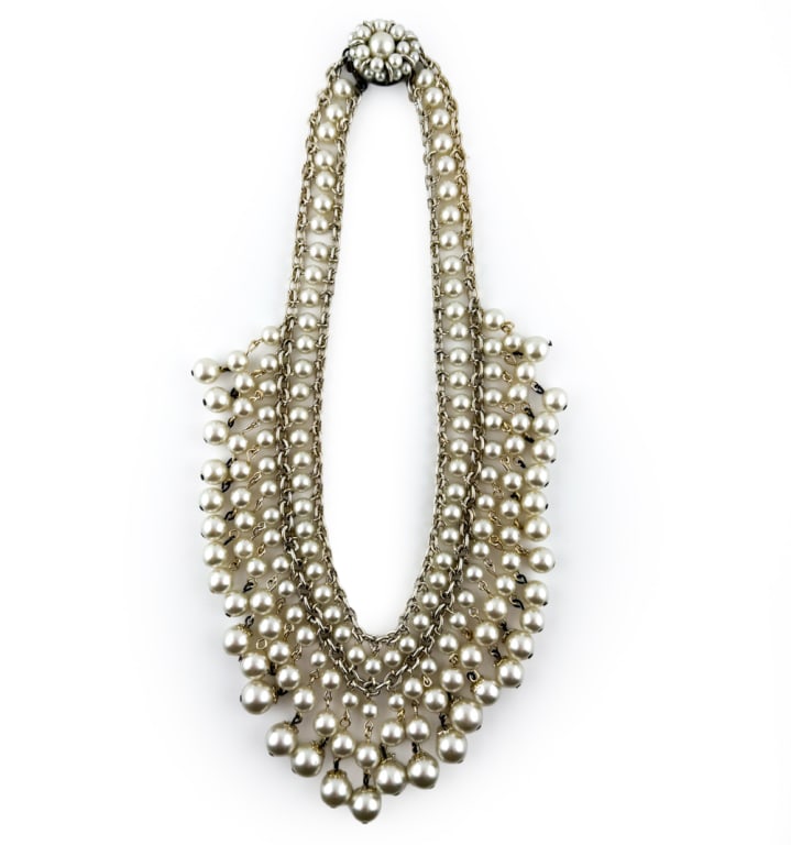 VINTAGE JAPANESE PEARL BIB NECKLACE: Bib necklace featuring many dangling pearls in a Cleopatra style with a floral form on clasp. Marked Japan on clasp. Dimensions: L 7" Condition: Tarnish to metal sections, light handling wear consiste