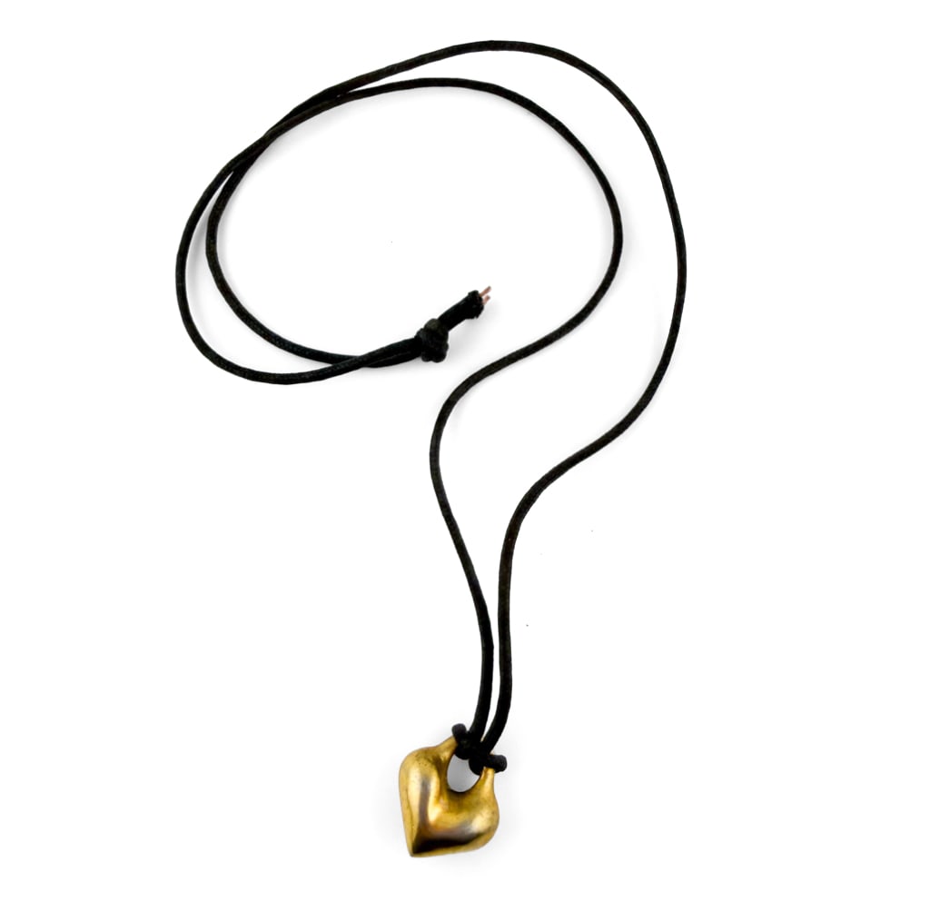 ROBERT LEE MORRIS HEART PENDANT: Black string necklace with a heart shaped pendant. Apparently unmarked. Dimensions: L 13" Condition: Some oxidation and slight discoloration to pendant. String with cuts at end after knot.