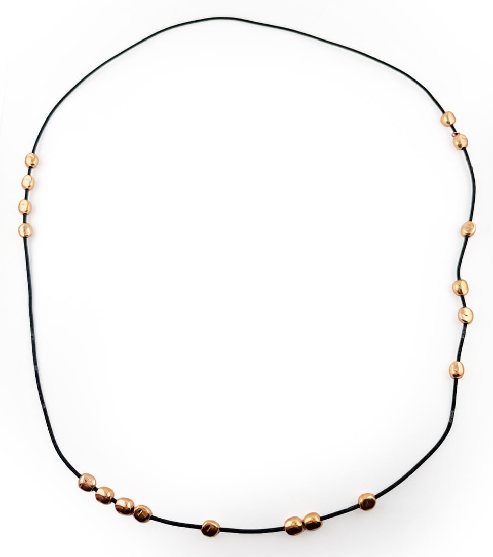 STYLE OF ROBERT LEE MORRIS ROSE GOLD-TONE NECKLACE: Beaded necklace in the style of Robert Lee Morris, featuring rose gold-tone small beads around a black string. Apparently unmarked. Dimensions: L 21" Condition: Wear consistent with age and use.
