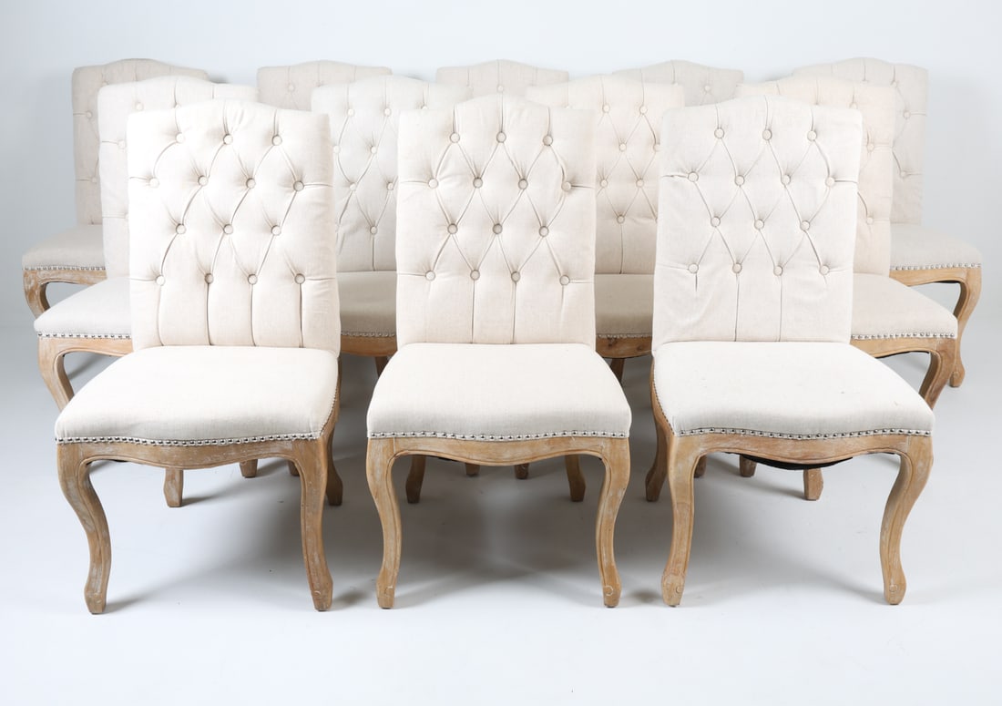 (12) CONTEMPORARY TUFTED DINING CHAIRS: Beige tufted fabric upholstery with carved legs in distressed finish. Dimensions: H 41" x W 18.5" x D 21" x SH 18.25". Condition: Few minor scuffs to legs.