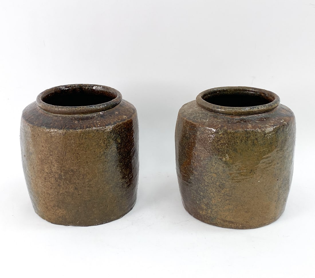 PAIR OF ALKALINE GLAZED STONEWARE JARS: Vintage handmade stoneware jars with an alkaline glaze, meant for storing rice, wine, beans, and grains. Both unmarked. Dimensions: H 10.75" x Dia 10" Condition: Small spots of glaze loss and imperfec