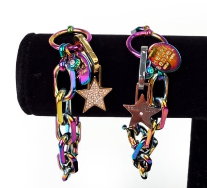 HENRI BENDEL INFLUENCER LINK BRACELETS: Pair of two iridescent colored bracelets with star charms with rhinestones. Both with metal tags reading Henri Bendel, New York. One with gold-tone star and other with silver-tone star. Dimensions: Di