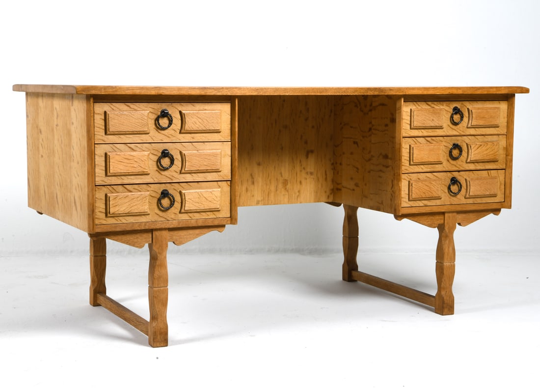 HENNING KJAERNULF DANISH OAK WRITING DESK C. 1970S: Key included. Turned legs and recessed panels carved to cabinet doors. Denmark, circa 1970s. Dimensions: H 29" x W 58.5" x D 29.5". Condition: Few water rings to top. Wear consistent with age and use.