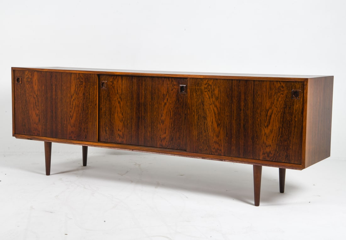 OMANN JUN STYLE DANISH ROSEWOOD SIDEBOARD C. 1960S: Rosewood sideboard with rounded inset cabinet door pulls. Adjustable shelves. Denmark, circa 1960s. Dimensions: H 30" x W 86.5" x D 19.75". Condition: Minor scuffs, good presentation overall. DMW183