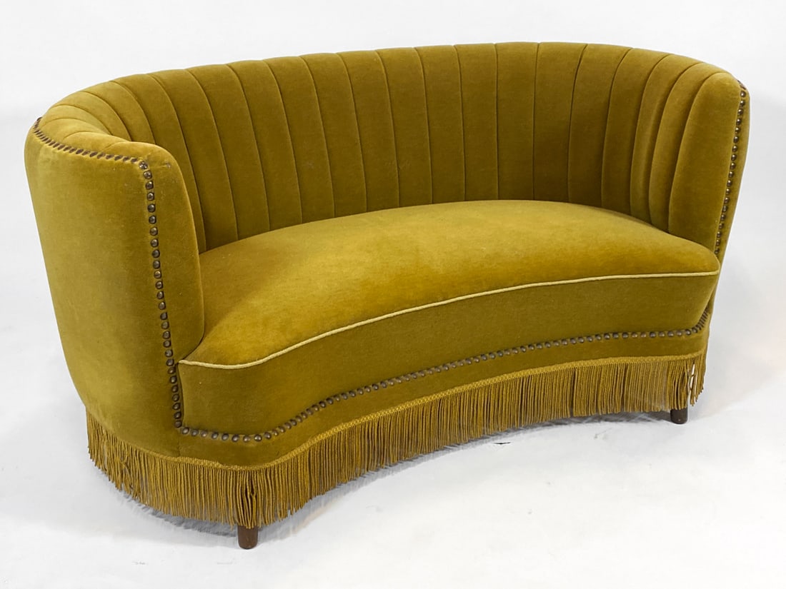DANISH VELOUR BANANA SOFA C. 1960S: Banana sofa with channel back design. Oak legs. Corded fringe skirt. Denmark, circa 1960s. Dimensions: H 29" x W 60" x D 29" x Sh 15.75". Conditions: Wear consistent with age and use, including few sc