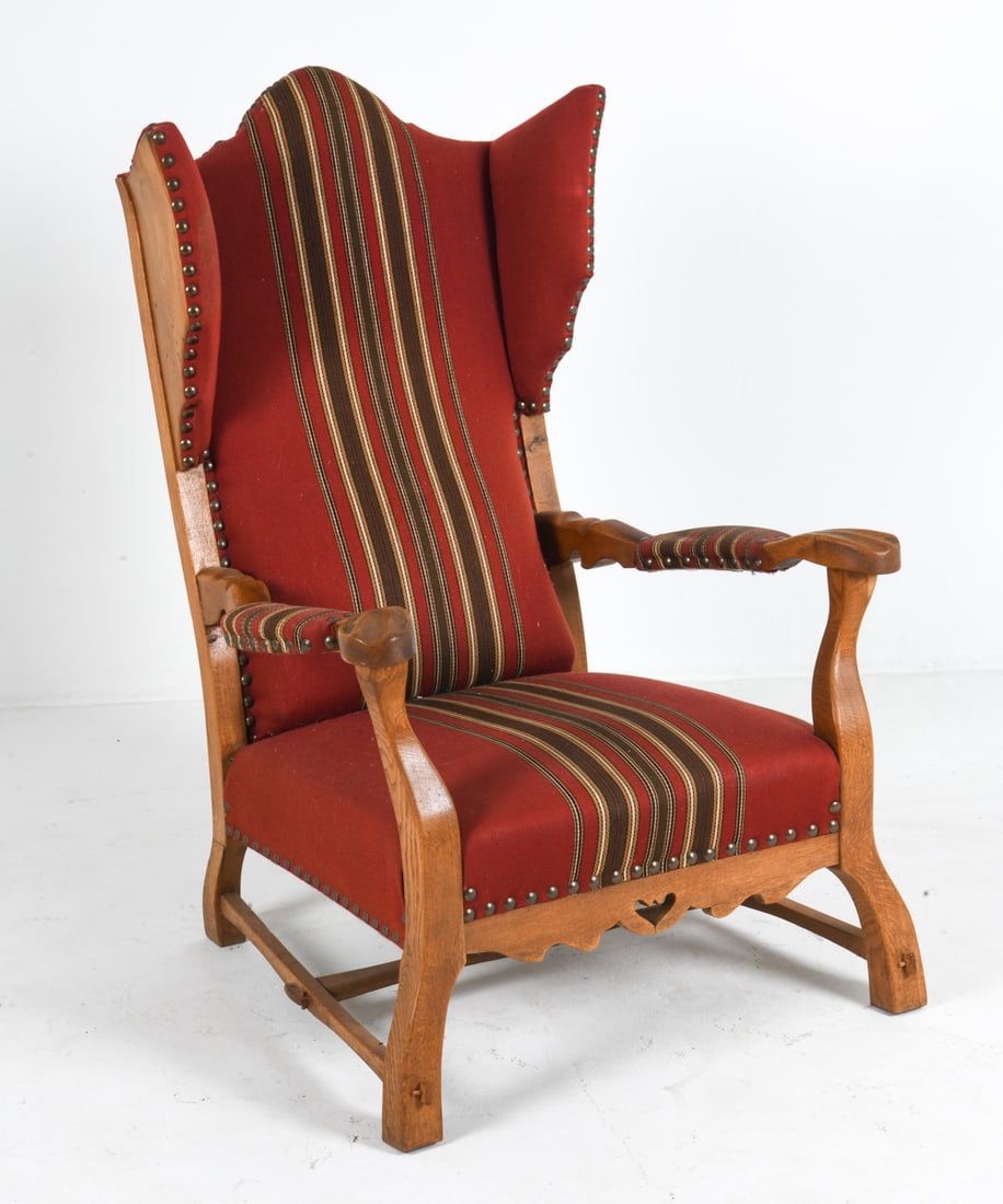 MANNER OF AXEL EINAR HJORTH WING-BACK LOUNGE CHAIR: Wingback lounge chair with oak frame. Cut out design to lower frame. Wool upholstery. Denmark, circa 1950s. Dimensions: H 45" x W 30.25" x D 31" x Sh 14.25". Condition: Wear consistent with age and us