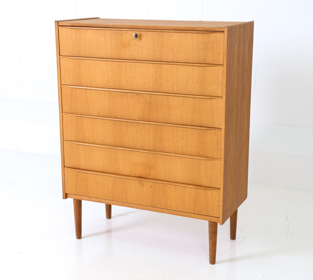MID-CENTURY DANISH OAK CHEST OF DRAWERS: 6-drawer chest made from oak with a lockable top drawer, on petite legs. Includes key. Denmark, circa 1950s. Dimensions: H 45.5" x W 35" x D 16.75" Condition: Very light wear consistent with age and u