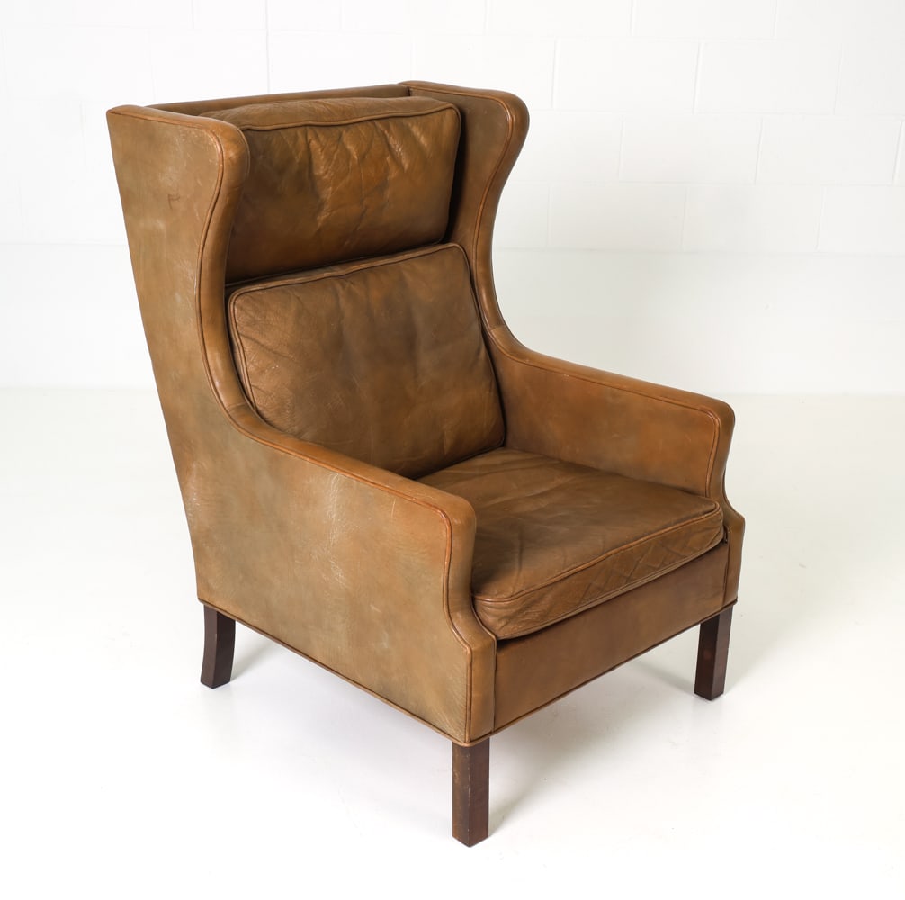 MOGENSEN STYLE DANISH LEATHER WINGBACK CHAIR: Leather wing back lounge chair. Denmark, circa 1970's. Dimensions: H 41" x W 28" x D 31" x SH 17" Condition: Signs wear consistent with age and use. Creasing and sun fading to cushions. soiling and a