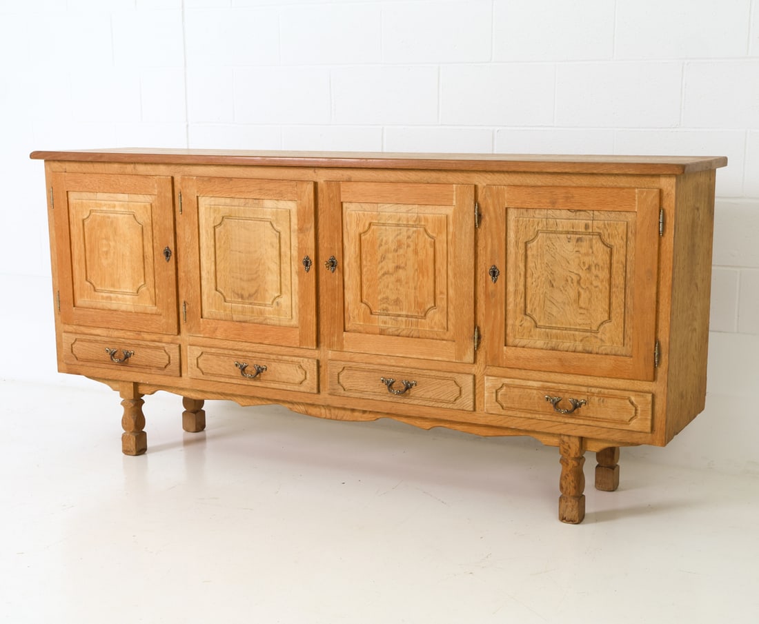 HENNING KJAERNULF DANISH OAK SIDEBOARD C. 1960S: For JK Mobler. Panel doors with sculpted legs and brass hardware. Marked on the back. Denmark, circa 1960s. Dimensions: H 36.75" x W 79" x D 17.75" Condition: Wear consistent with age and use, includi
