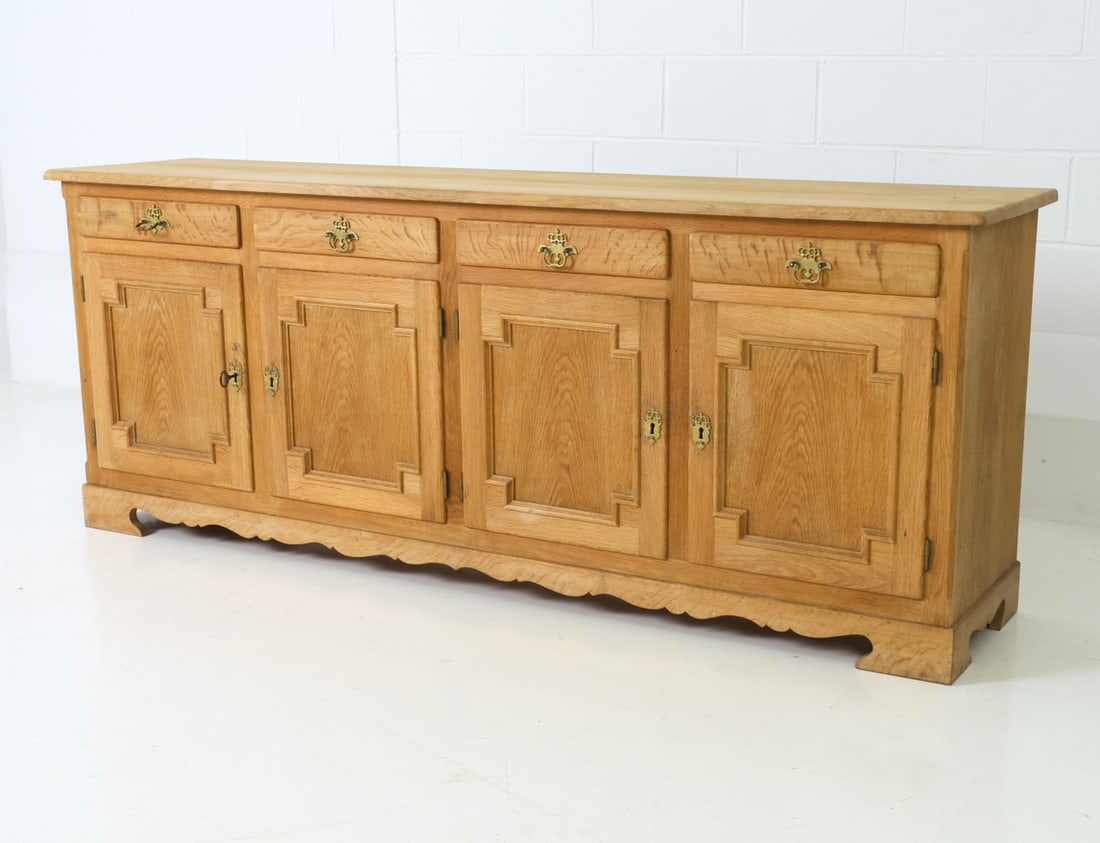 HUNDSTRUP MOBLER DANISH OAK SIDEBOARD C. 1970S: Includes two keys. Paneled doors with scalloped lower edges. Marked to the back. Denmark, circa 1970s. Dimensions: H 30.75" x W 79" x D 17.75" Condition: Wear consistent with age and use, including sl