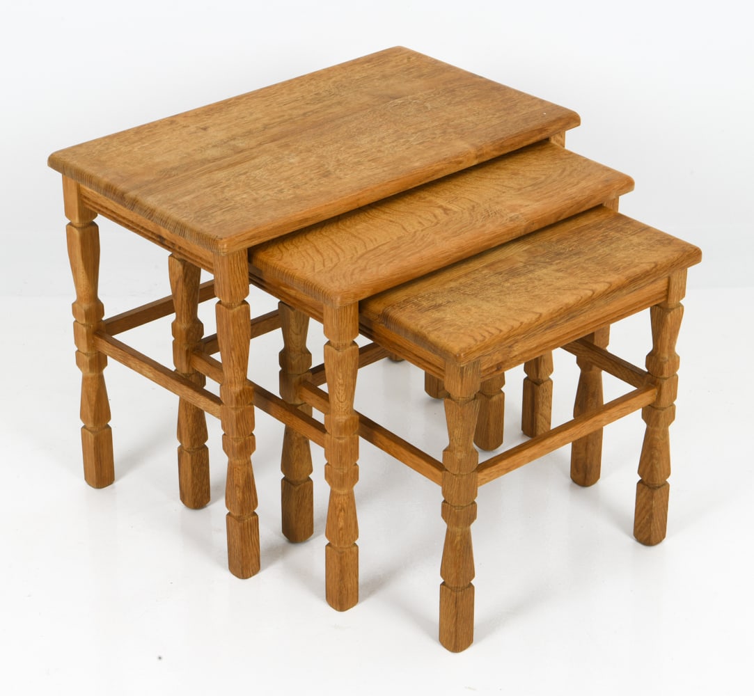 (3) STYLE OF KJAERNULF DANISH OAK NESTING TABLES: Set of three nesting tables in sculpted oak turned legs and stretchers. Denmark, circa 1970's. Dimensions: H 18.5" x W 23.5" x D 14" Condition: Wear consistent with age and use including water spots,