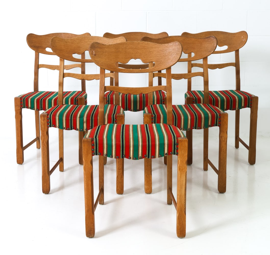 (6) KJAERNULF STYLE DANISH OAK DINING CHAIRS 1970S: Six oak dining chairs, featuring a curved design to backrest and striped upholstery with brass studded accents. Denmark, circa 1970s. Dimensions: H 34" x W 18.5" x D 22" x Sh 18" Condition: Wear consi