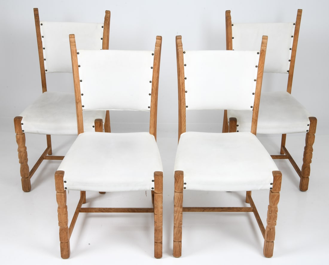 (4) ATTR. HENNING KJAERNULF OAK DINING CHAIRS: Grouping of (4) oak dining chairs with carved frames and a white vinyl upholstery. Dimensions: H 36.75" x W 17.5" x D 21" x Sh 16.75" Condition: Wear consistent with age and use including rubs and scu