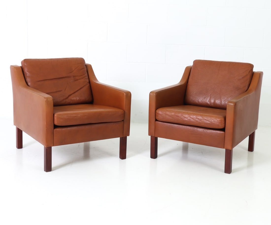 PAIR BORGE MOGENSEN STYLE DANISH LOUNGE CHAIRS: Leather upholstered lounge chairs in oak frame with dark stained finish legs. Denmark, circa 1970s. Dimensions : H 27.5" x W 26.25" x D 30.5" x SH 15.5" Condition: Minor indent to leather seats, 3 inc