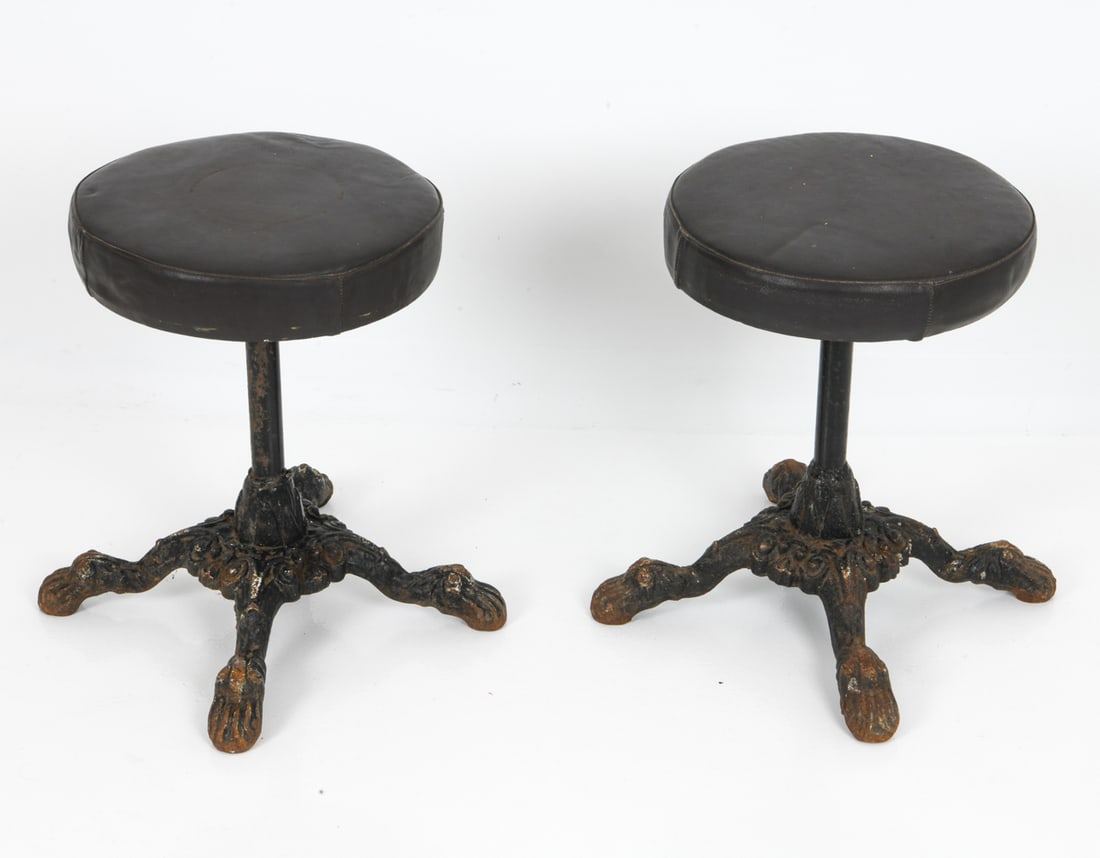 PAIR OF ANTIQUE CAST IRON & LEATHER STOOLS: Leather upholstered tops with black painted cast iron bases. Dimensions: H 19" x DIA. 14" Condition: Wear consistent with age and use including loss of paint to legs and oxidation. G161