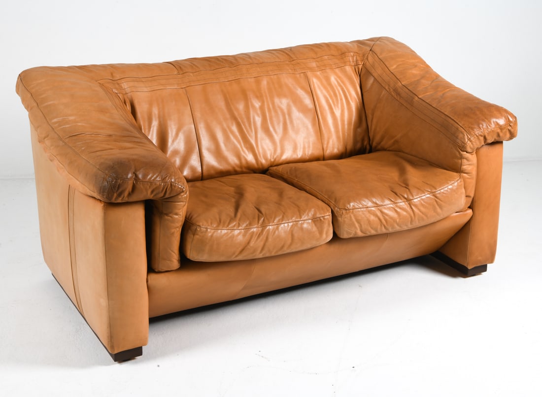 DE SEDE STYLE DANISH LEATHER LOVESEAT C. 1960S: Cognac leather sofa with beech feet. Denmark, circa 1960s. Dimensions: H 34.75" x W 65.5" x D 38" x Sh 18.25". Condition: Wear consistent with age and use including minor rubs and scuffs. Slight fadin