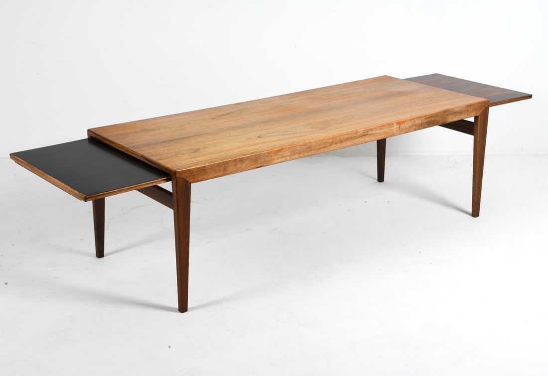 JOHANNES ANDERSEN ROSEWOOD COFFEE TABLE C. 1960S: Rosewood coffee table with trays or leaves that extend out from sides. Apparently unmarked. Denmark, circa 1960s. Dimensions: H 20" x W 59" x D 24". Leaves W 15.25". Condition: Sun Fading to top.