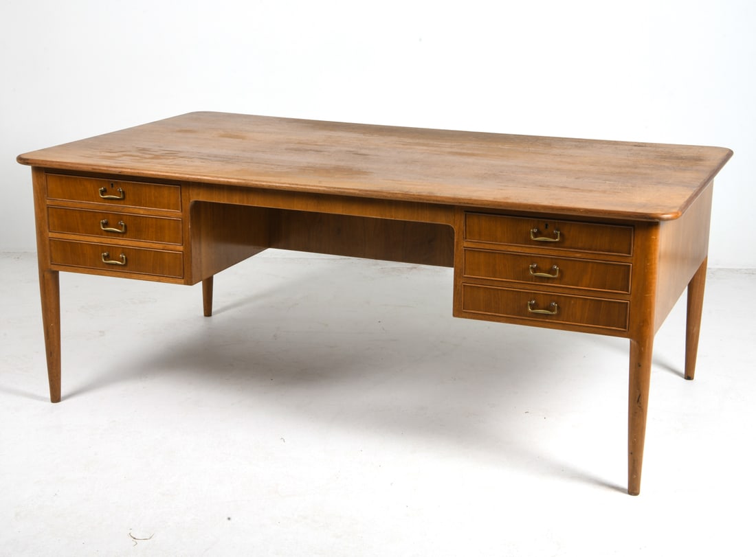 HENNINGSEN STYLE DANISH WALNUT WRITING DESK 1960S: Key included. Walnut writing desk with brass pulls for oak drawers. Denmark, circa 1960s. Dimensions: H 29.5" x W 75" x D 43.25". Conditions: Wear consistent with age and use including minor dings