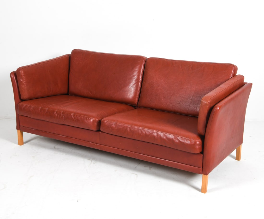 ATTR. MOGENS HANSEN DANISH LEATHER SOFA C. 1960S: Red leather sofa with beech legs. Apparently unmarked. Denmark, circa 1960s. Dimensions: H 24.75" x W 72" x D 29.5" x Sh 14.5". Condition: Wear consistent with age and use including rubs, creasing and