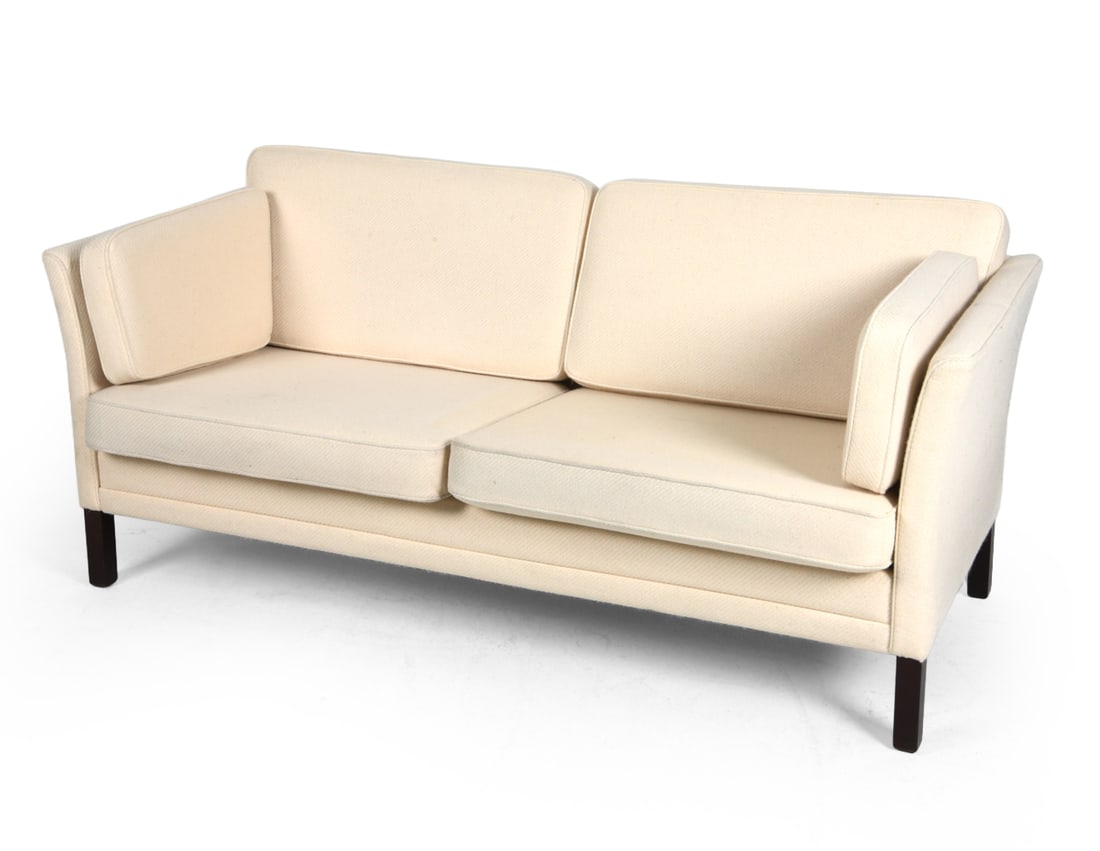 MOGENS HANSEN STYLE DANISH SOFA C. 1970S: Beech feet with white colored upholstery. Denmark, circa 1970s. Dimensions: H 27.5" x W 69.5" x D 29.75" x Sh 17". Condition: Wear consistent with age and use including minor scratches and rubs to