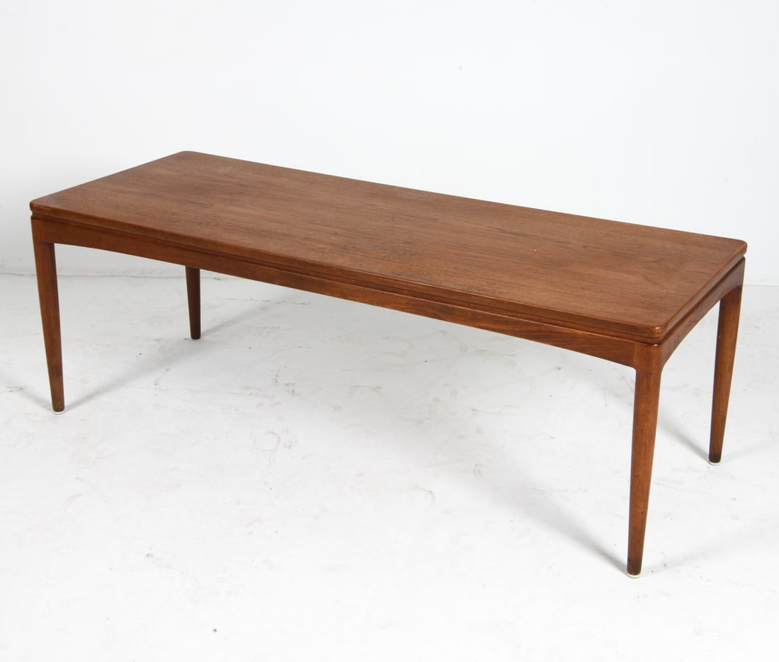 JOHANNES ANDERSEN STYLE DANISH TEAK COFFEE TABLE: (1) Leaf with black top included, stored within table. Denmark, circa 1960s. Dimensions: H 20.5" x W 58.5" x D 22.5". Leaf W 19.75". Condition: Minor scuffs and surface scratches, wear consistent with