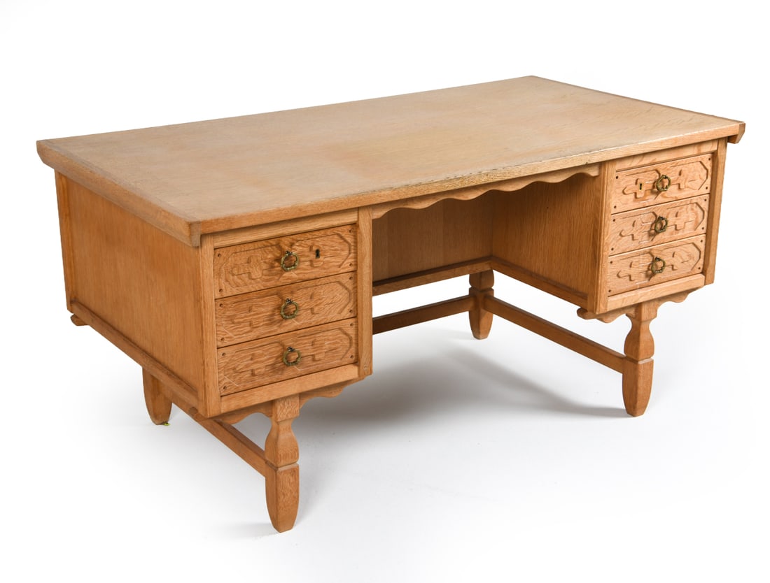 HENNING KJARENULF DANISH OAK WRITING DESK C. 1970S: Key included. Oak writing desk with carved decoration to drawer fronts. Brass ring pulls. Apparently unmarked. Denmark, circa 1970s. Dimensions: H 29.5" x W 59" x D 31.25". Condition: Wear consistent