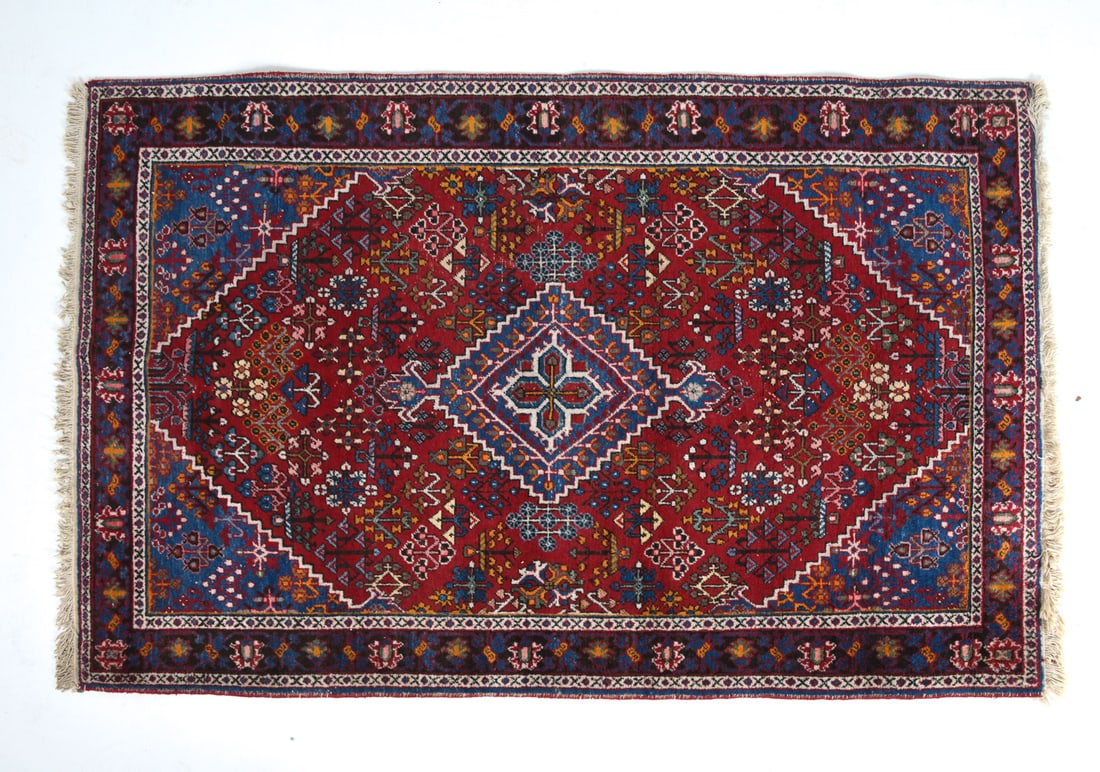 20TH CENTURY ORIENTAL RUG: Hand-knotted wool rug with red, beige, and blue geometric designs. 20th century. Dimensions: L 84" x W 52". Condition: Minor sun fading, few losses to fringe. Wear consistent with age and use.