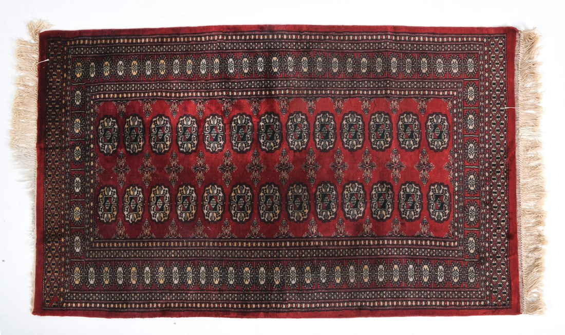 BOKHARA ORIENTAL RUG: Hand-knotted wool rug with traditional gul pattern. 20th century. Dimensions: L 66" x W 36". Condition: Losses to fringe, minor losses and wear to pile. Wear consistent with age and use.