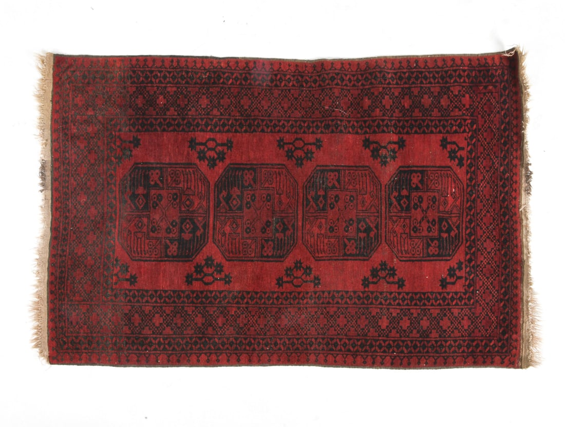 ORIENTAL RUG: Red oriental rug in red and black geometric design. 20th century. Dimensions: L 75" x W 46". Condition: Losses and discoloration to fringe. Needs cleaning. Wear consistent with age and use.