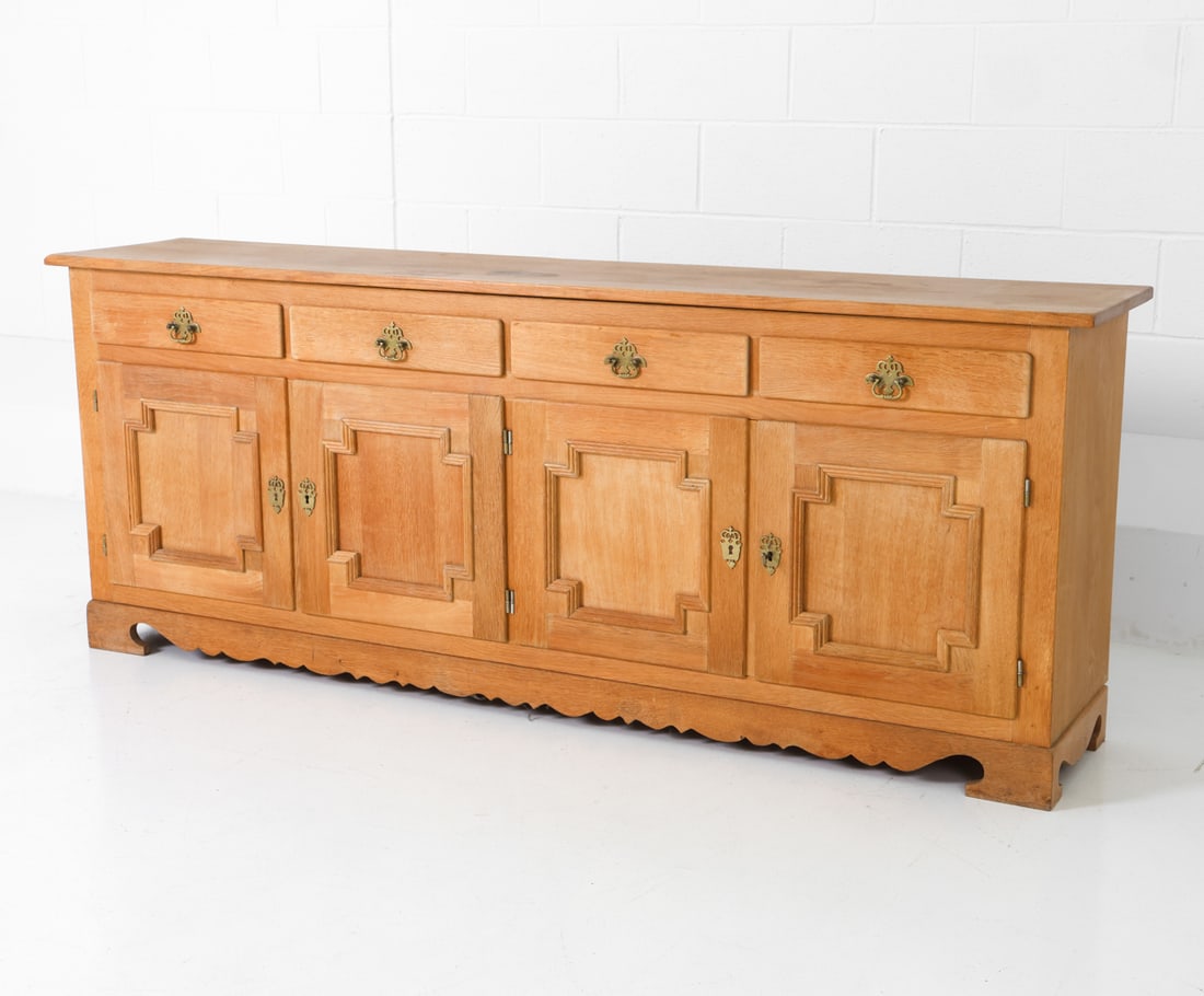ATTR. HENNING KJAERNULF DANISH OAK SIDEBOARD 1960S: Oak frame with carved panel doors and brass hardware. Denmark, circa 1960s. Dimensions: H 31" x W 79" x D 16" Condition: Water marks and stains to surface. Wear consistent with age and use.