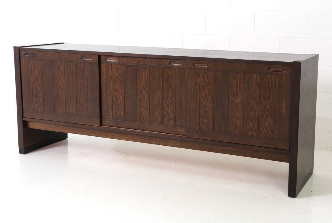 SKOVBY DANISH OAK SIDEBOARD C. 1960S: Stained oak frame. Three sliding doors with adjustable shelves and two drawers inside. Apparently unmarked. Denmark, circa 1960s. Dimensions: H 30" x W 77.25" x D 19" Condition: Wear consistent with a