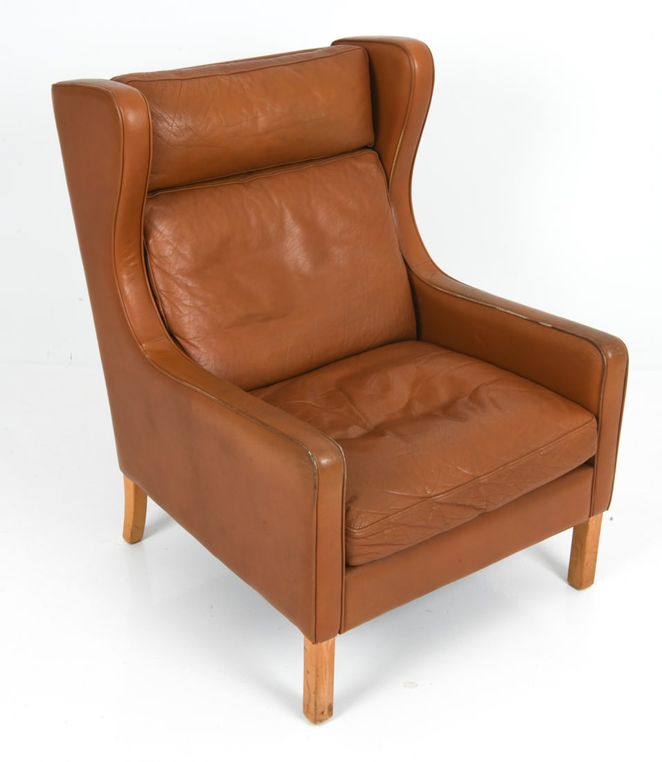 GEORG THAMS DANISH LEATHER WINGBACK CHAIR C. 1970S: High back lounge armchair with tan leather upholstery and beech legs. Marked underneath. Denmark, circa 1970s. Dimensions: H 38.5" x W 28.25" x D 34" x Sh 15.5" Condition: Rubs and scuffs to trim of a