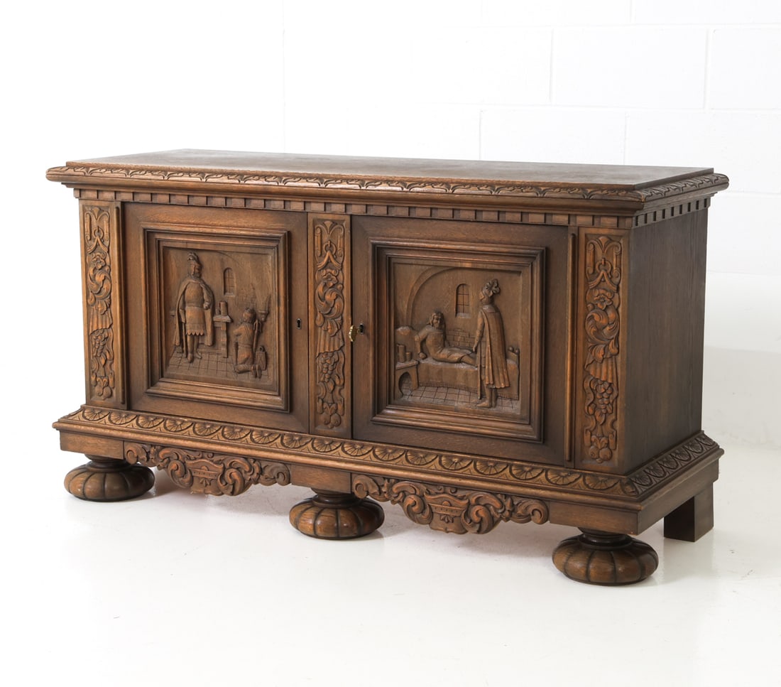RENAISSANCE REVIVAL STYLE DANISH OAK SIDEBOARD: A Key Included. Oak frame with figurative relief carved panels on the doors. Architectural moldings and scrolling foliage. 6 drawers inside. Denmark, 20th century. Dimensions: H 29" x W 53.25" x D 18.
