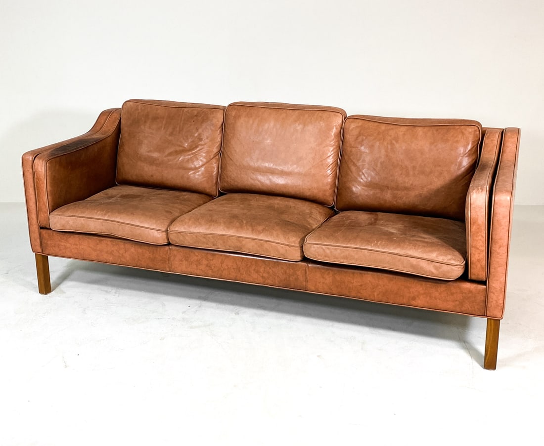 ATTR. BORGE MOGENSEN DANISH LEATHER SOFA 1970S: Cognac leather sofa with beech legs. Apparently unmarked. Denmark, circa 1970s. Dimensions: H 32" x W 84.5" x D 32" x SH 18.25". Condition: Discolored spots, sun-fading and scuffs to wood and leather.