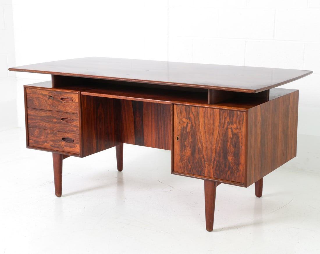 DANISH ROSEWOOD WRITING DESK C. 1960S: A key included. Floating top writing desk with three drawers and a storage cabinet. Open compartment with shelves and drop-down door cabinet to the backside. Denmark, circa 1960s. Dimensions: H 28.5"