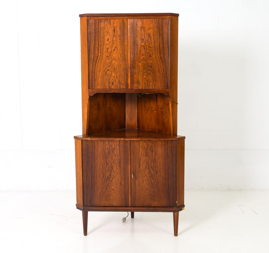 BRDR DANISH ROSEWOOD CORNER CABINET: Includes a key. Featuring two cabinets with doors and shelves inside. Rosewood frame. Marked to the light compartment in open shelving section. Denmark, circa 1980's. Dimensions: H 66" x W 34" x D 22"
