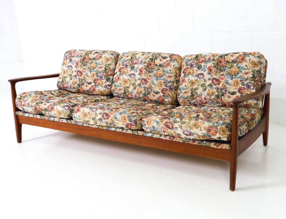 STYLE OF FOLKE OHLSSON SWEDISH TEAK SOFA C. 1960S: Three-seater sofa with sculpted armrests and floral upholstery. Sweden, circa 1960s. Dimensions: H 29" x W 81" x D 30" x SH 16" Condition: Wear consistent with age and use. Pulled threads to cushionin