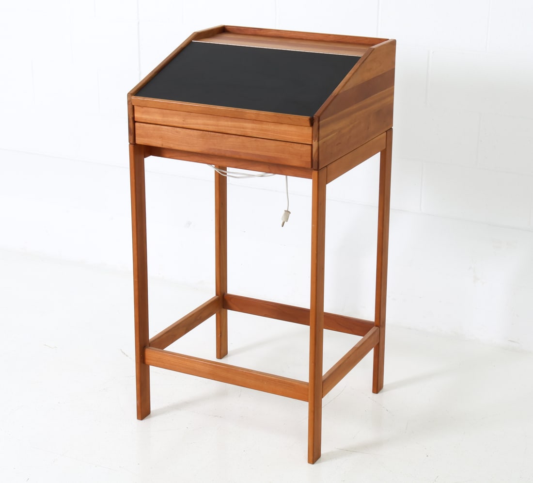 STYLE OF ANDREAS HANSEN BEECH STANDING DESK: Black linoleum-type flip-up inset surface and a single drawer. Light compartment under the drawer. Denmark. Dimensions: H 45" x W 23.5" x D 22.5" Condition: Wear consistent with age and use. European