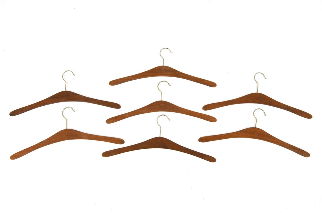 VINTAGE DANISH TEAK COAT HANGERS: Grouping of (7) teak hangers with brass hooks. Dimensions: H 7" x W 17.25" Condition: Wear consistent with age and use including light surface marks.