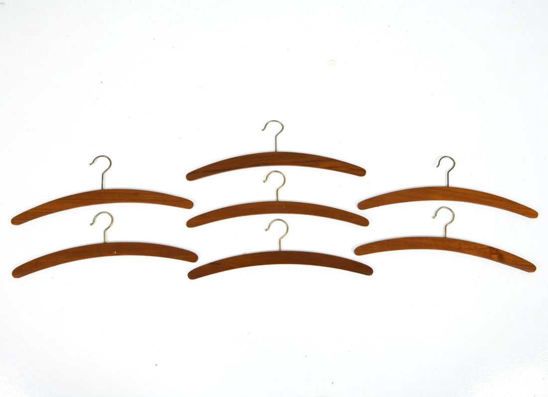 VINTAGE DANISH TEAK COAT HANGERS: Grouping of (7) teak hangers with brass-tone hooks. Dimensions: H 5.75" x W 17.5" Condition: Wear consistent with age and use including minor surface wear and rubs.