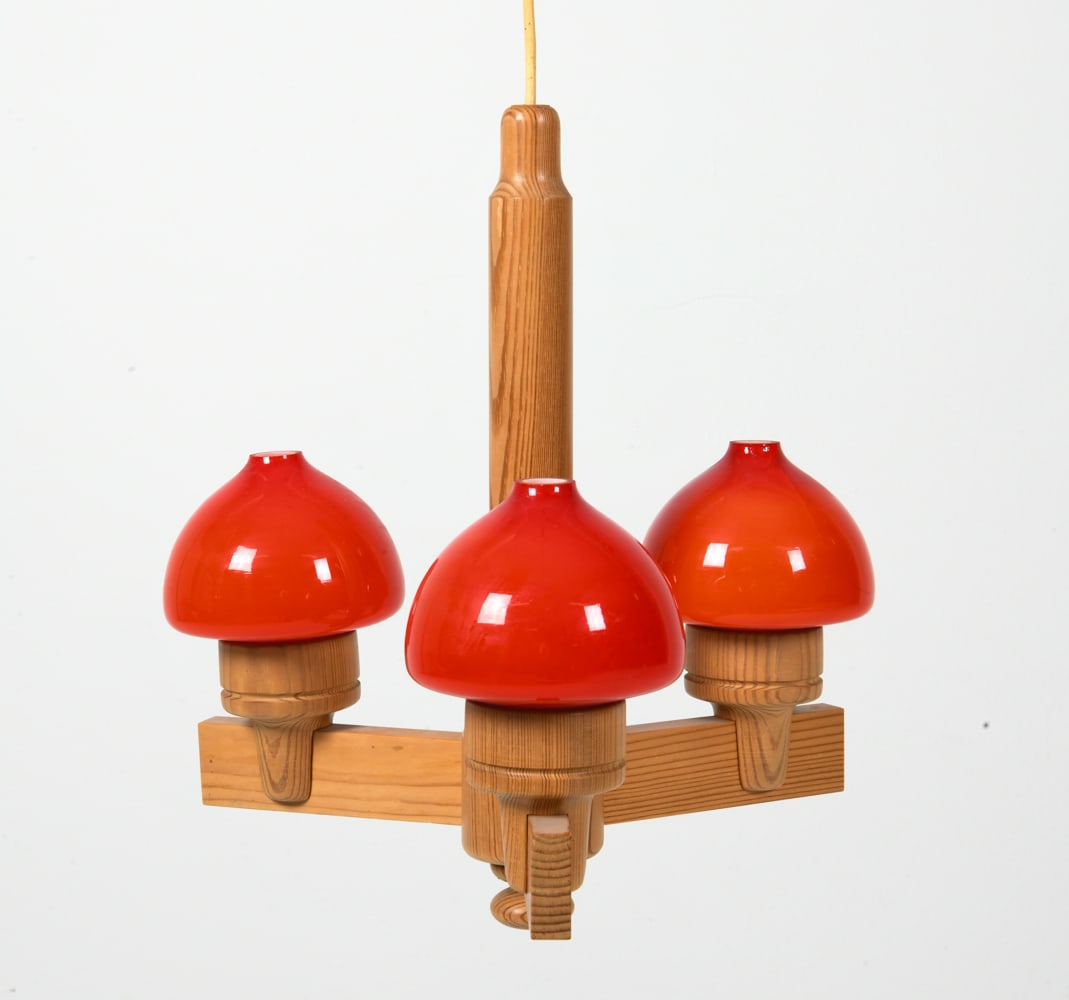 UNO DAHLEN ANETA PINE & GLASS CHANDELIER C. 1970S: Designed by Uno Dahlen for Aneta. Pine chandelier with red glass shades. Tagged to wood. Sweden, circa 1970s. Dimensions: H 17.5" x Dia. 13". Condition: Wiring untested. Few scuffs and dings to wood.