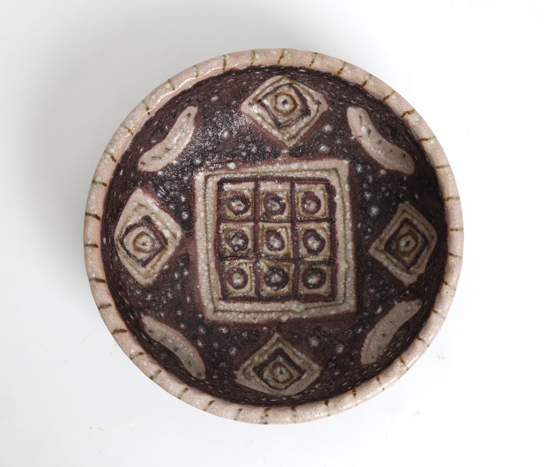 GUIDO GAMBONE (ITALY, 1909-1969) STONEWARE BOWL: Textured and cratered exterior in brown and cream tones. Geometric pattern with squares and circular motifs on a speckled brown and white glazed background. Signed Donkey mark to the underside.