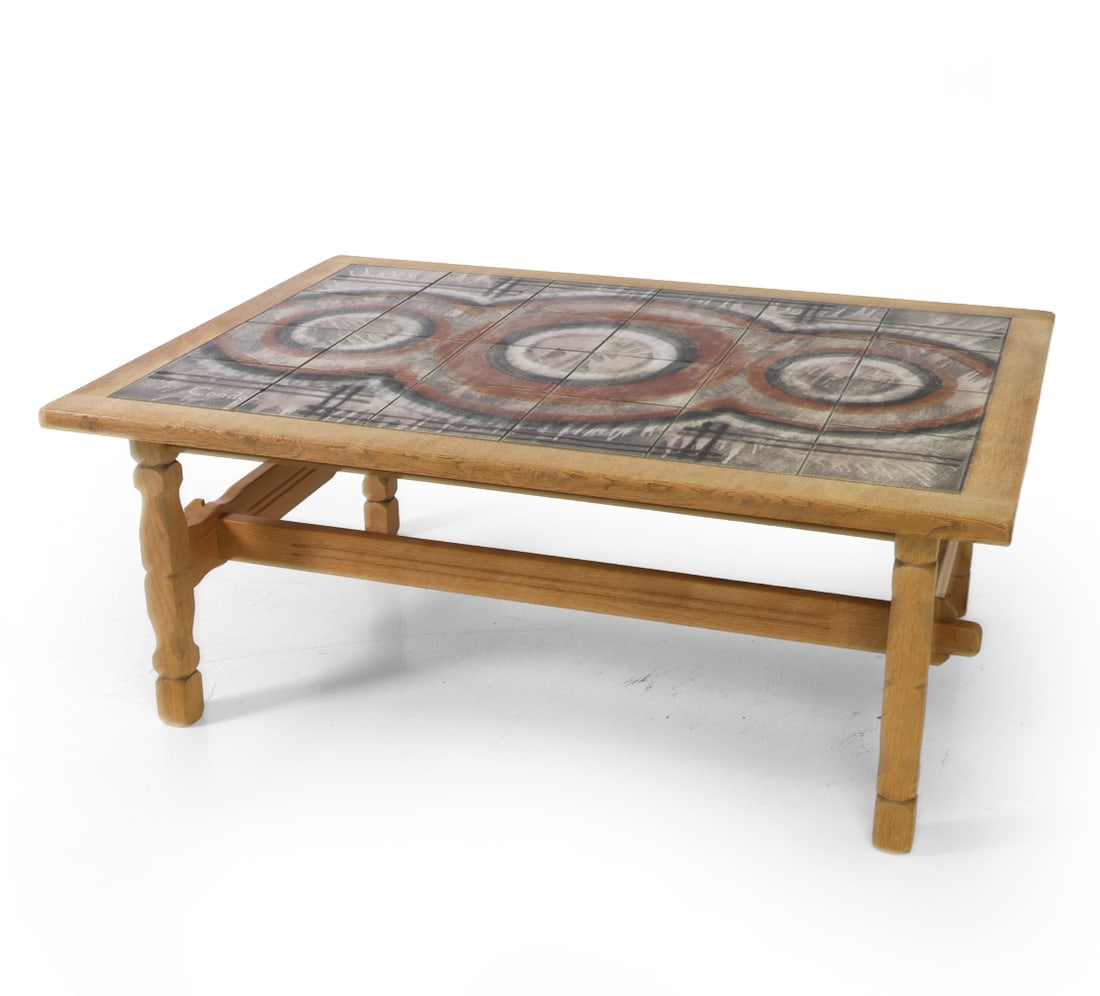 STYLE OF KJAERNULF OAK & TILE COFFEE TABLE C.1960S: Oak frame with carved legs and ceramic tile top. Signed to tile top. Denmark, circa 1960s. Dimensions: H 21.5" x W 53.5" x D 37.5" Condition: Rubs and scuffs to legs. Watermarks, fading. Wear consiste