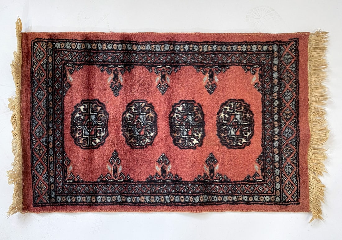 HAND-KNOTTED BALUCH AFGHAN WOOL RUG: Wool rug with salmon pink, blue, and white geometric designs. Mid 20th century. Dimensions: L 18" x W 31". Condition: Slight discoloration to fringe. Wear consistent with age and use.