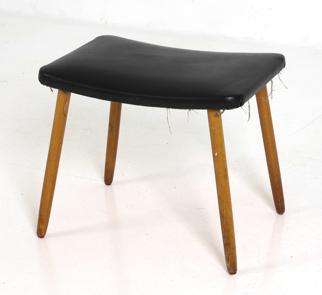 MID-CENTURY DANISH FOOTSTOOL C. 1960S: Footstool or ottoman with a black vinyl upholstered seat. Dimensions: H 16" x W 18.5" x D 13.25" Condition: Wear consistent with age and use including rubs and dings to legs. Fraying and soiling to