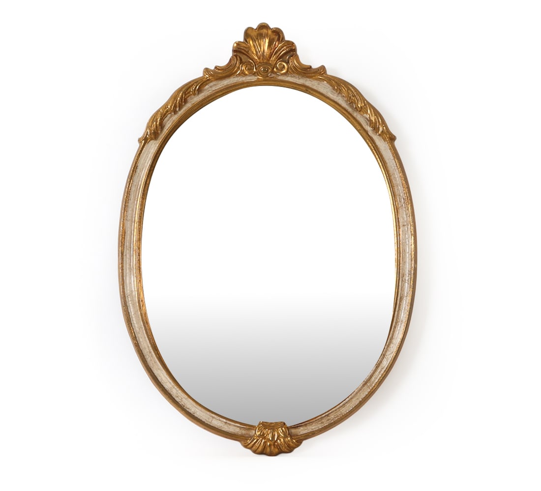 FRENCH STYLE OVAL GILT WALL MIRROR: Features a molded frame with a delicate shell design at the top and bottom. European, circa 1950's. Dimensions: H 23.75" x W 16.25" Condition: Wear consistent with age and use including minor rubs